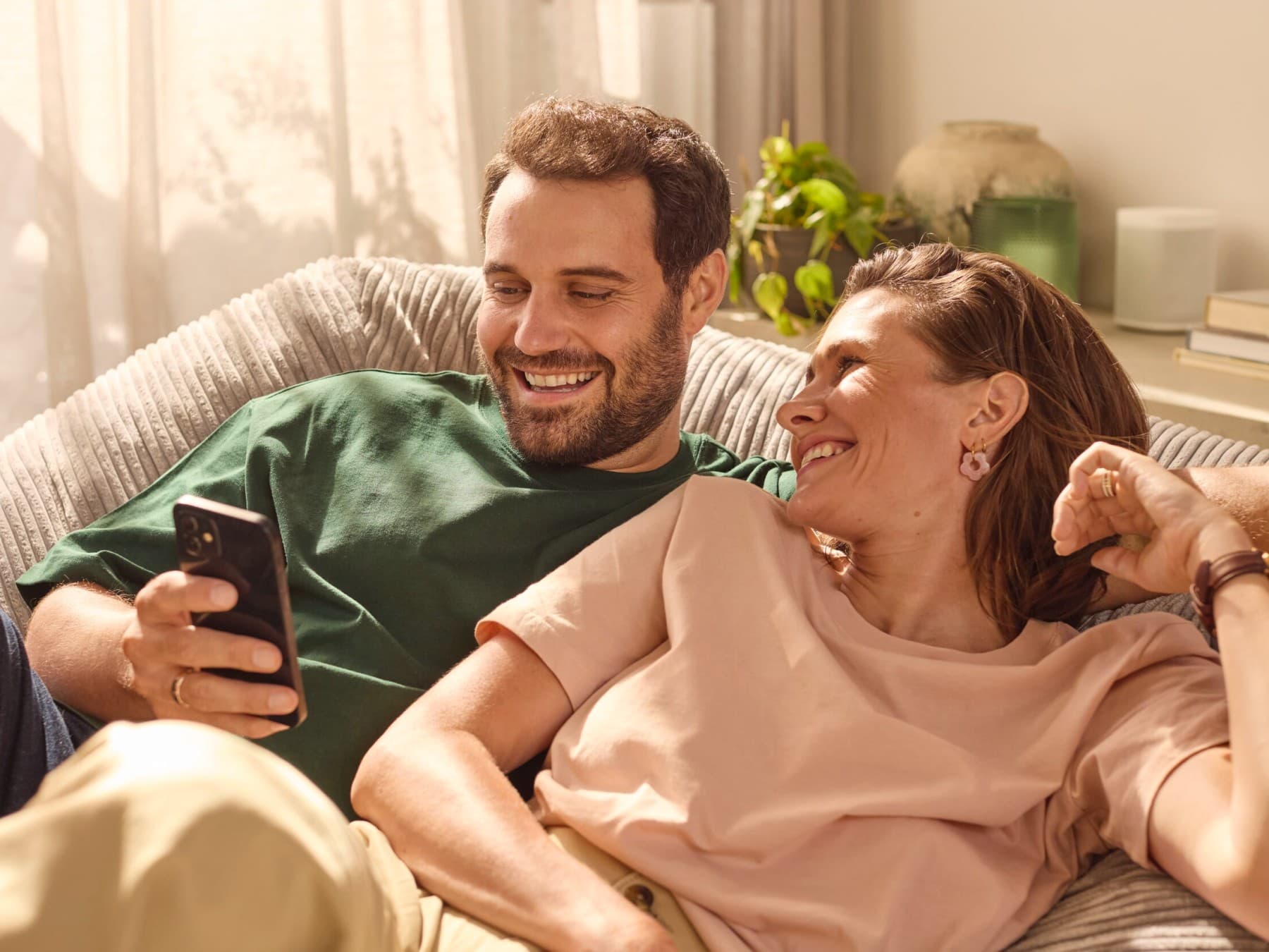 Pareja sentada en el sofá comprobando el consumo energético en una aplicación.