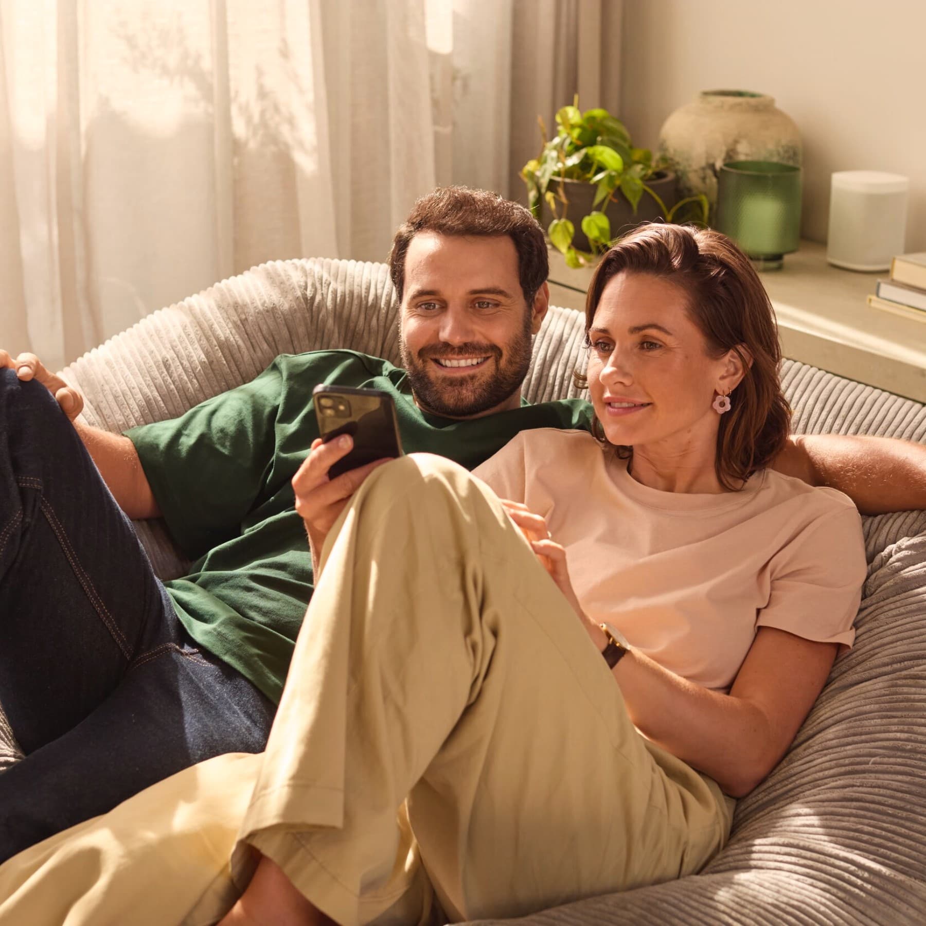 Una pareja sentada junta mirando sus teléfonos.