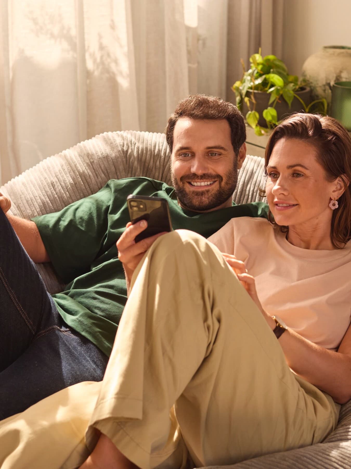 Pareja sentada en un sofá mirando un smartphone