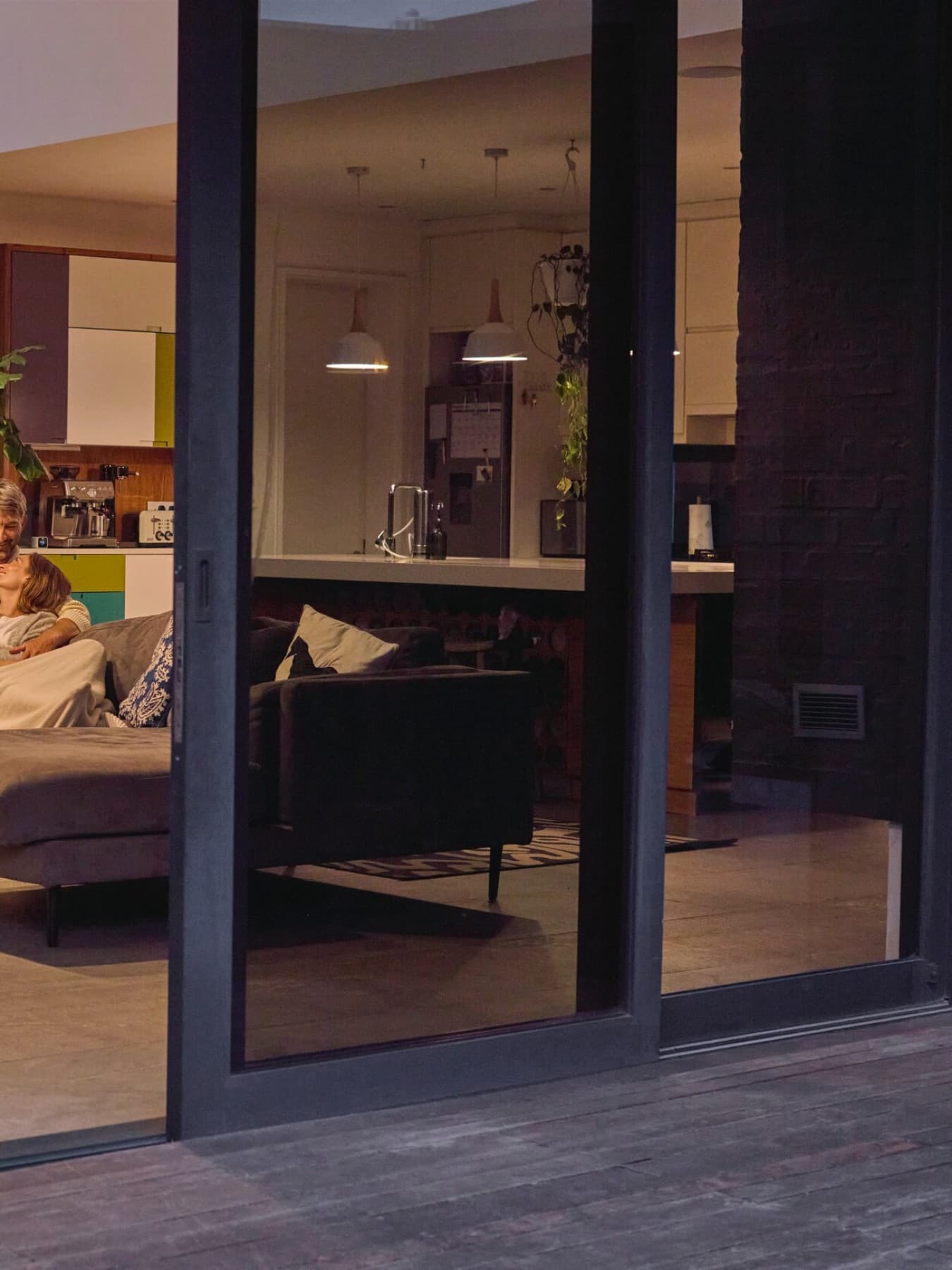 Pareja sentada en el sofá con la puerta del patio abierta.