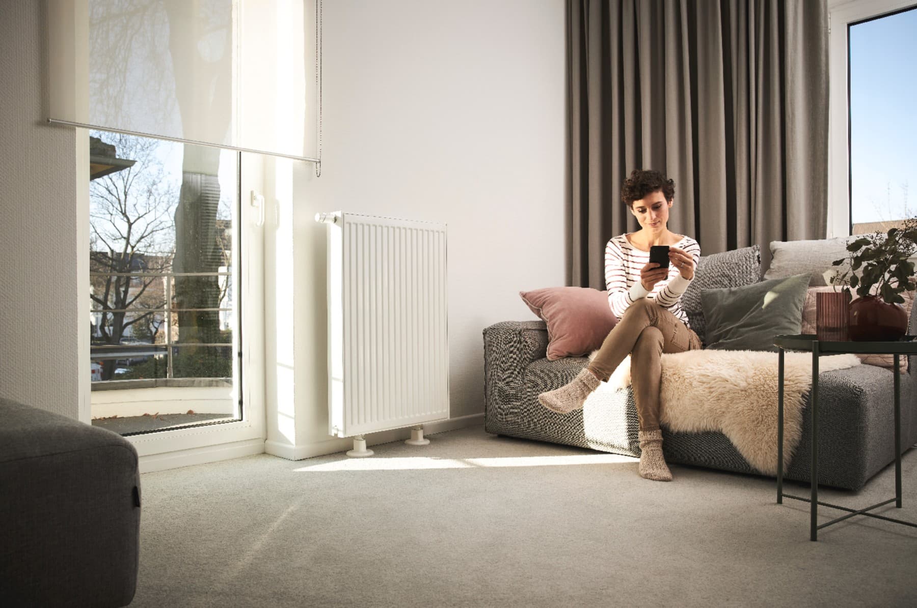 Mujer sentada en un sofá controlando la temperatura