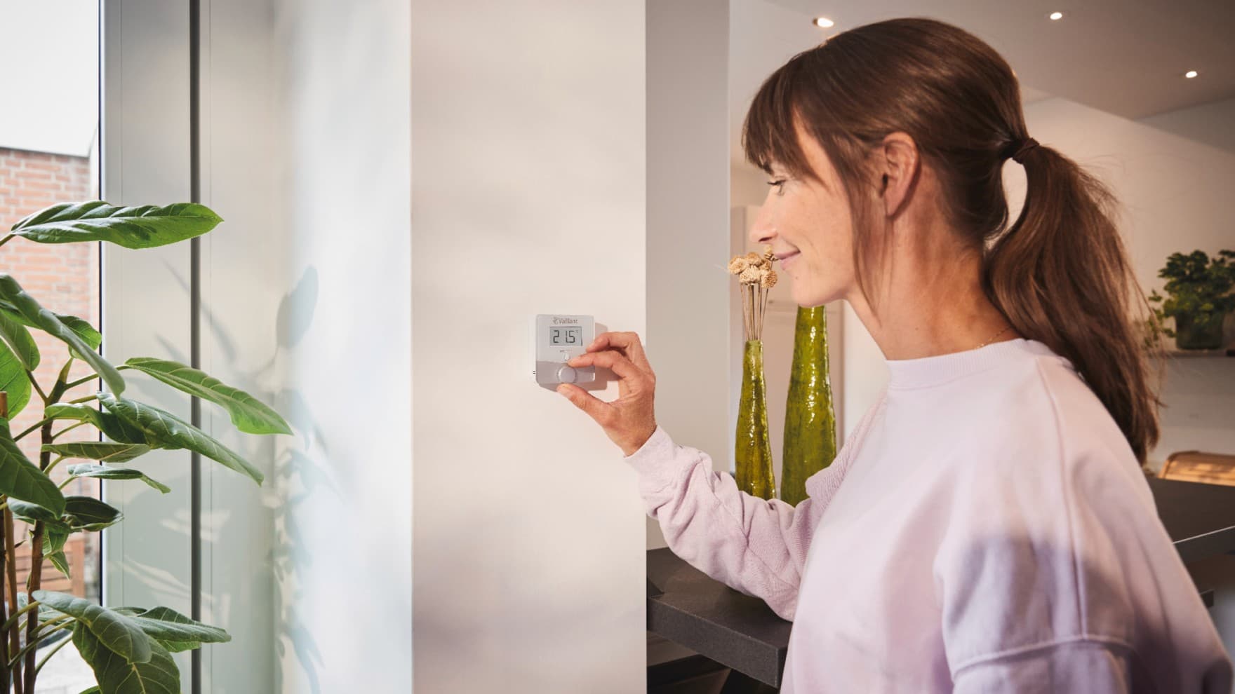 Mujer utilizando el termostato sensoROOM de Vaillant.