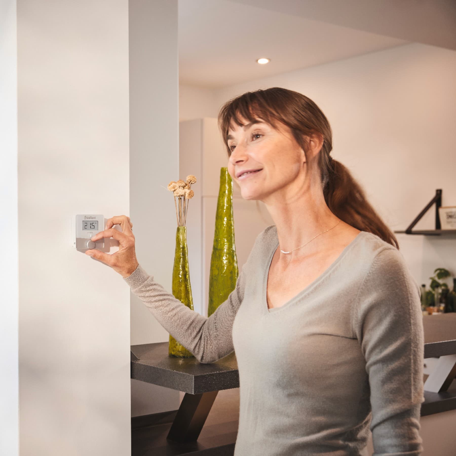 Mujer girando un termostato en la pared