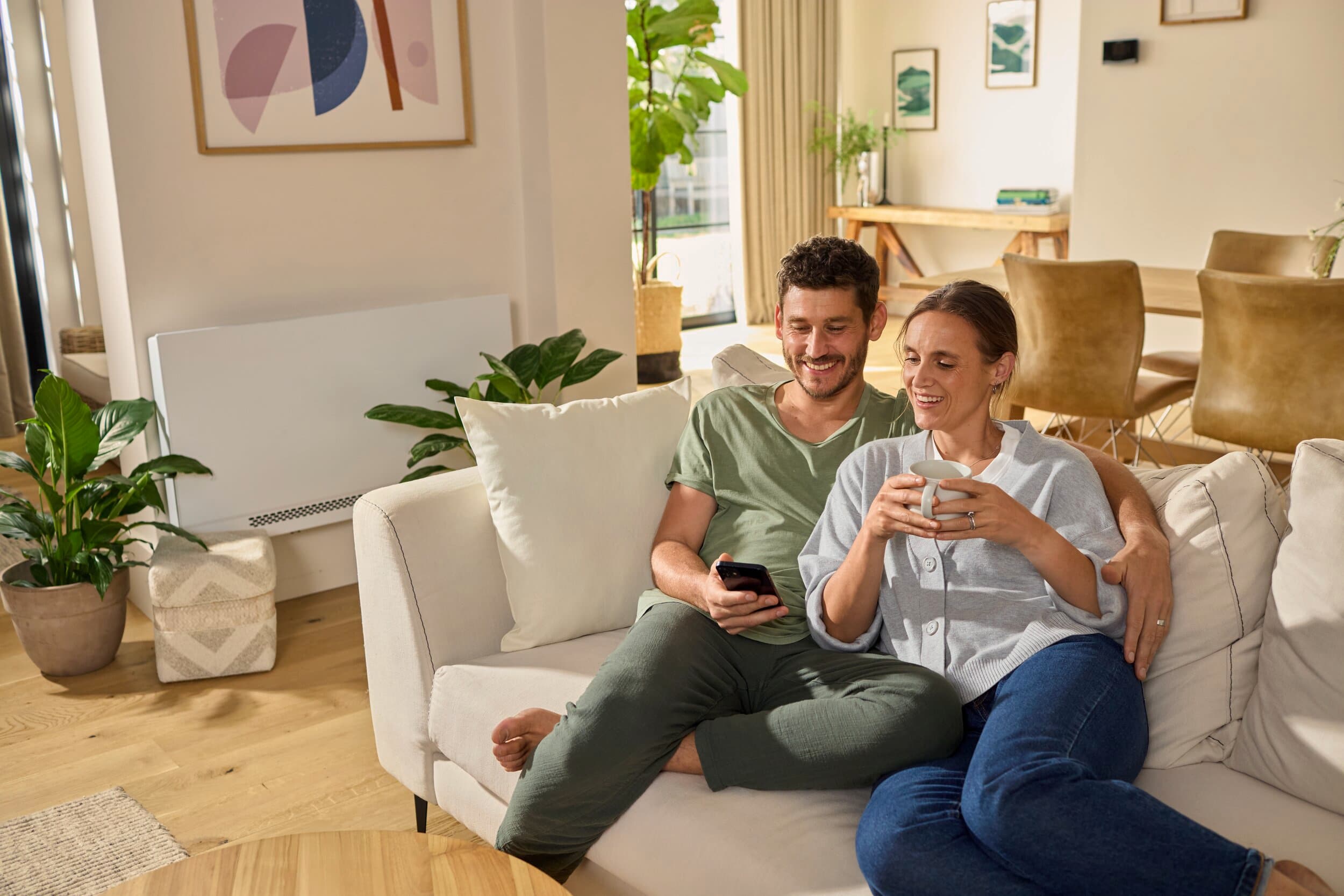 Una pareja sentada en el sofá mirando un smartphone
