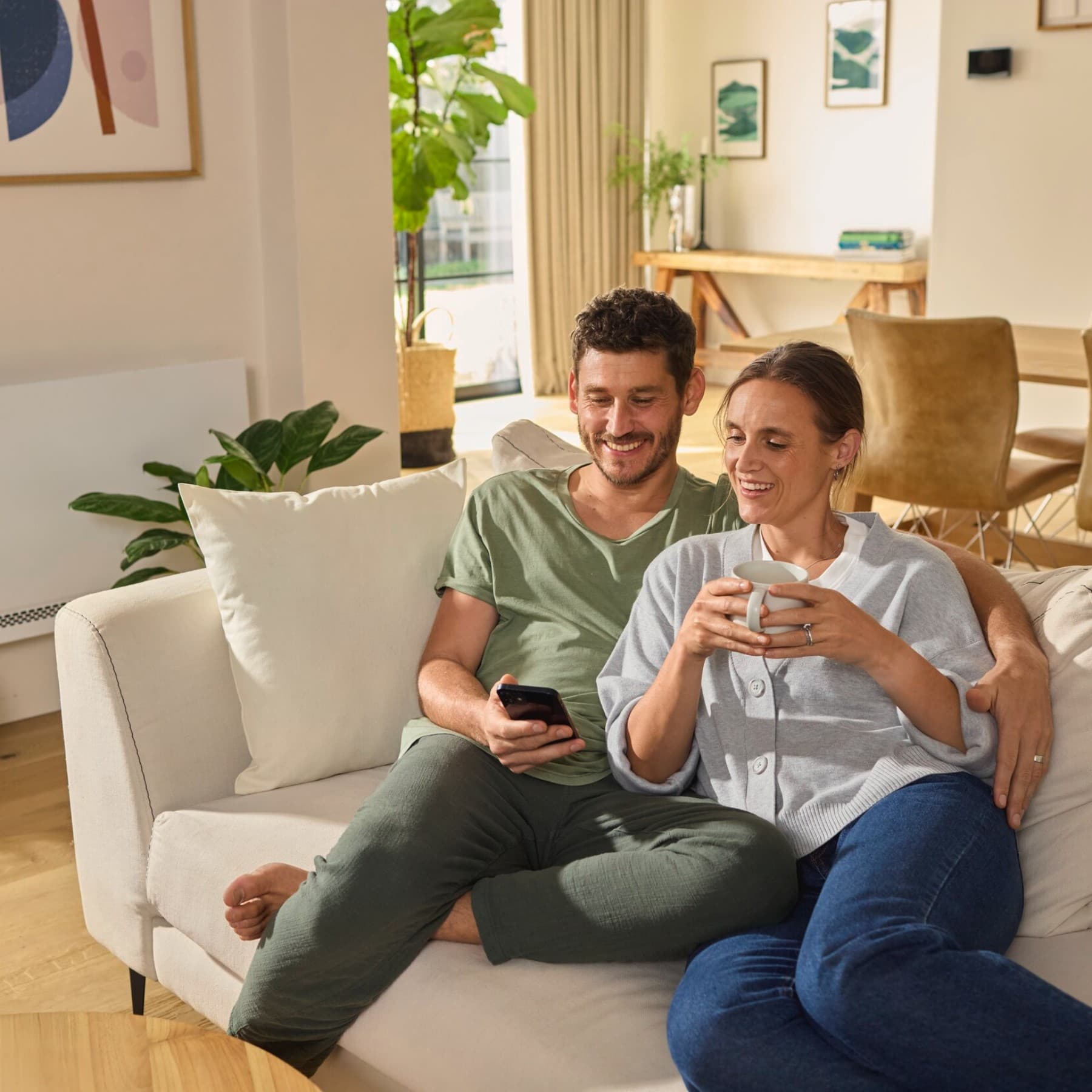 Una pareja sentada en el sofá mirando un smartphone