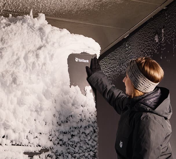 Una mujer quitando el hielo de una bomba de calor