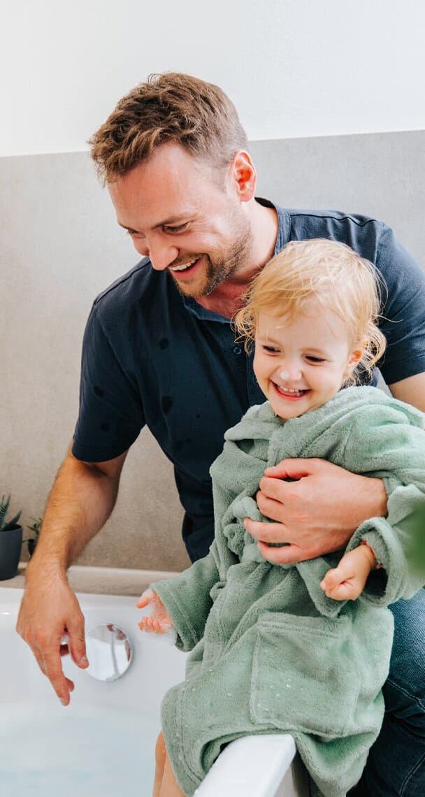 Un padre y su hijo sentados junto a la bañera.