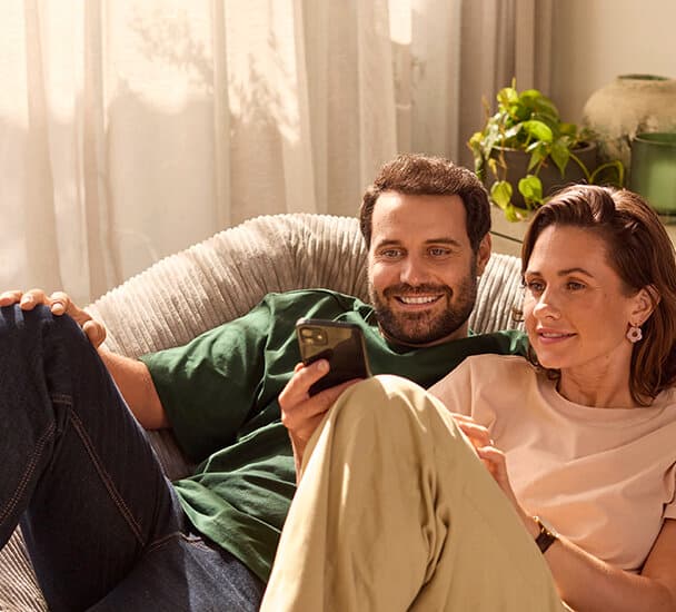 Una pareja sentada en el sofá mirando un smartphone