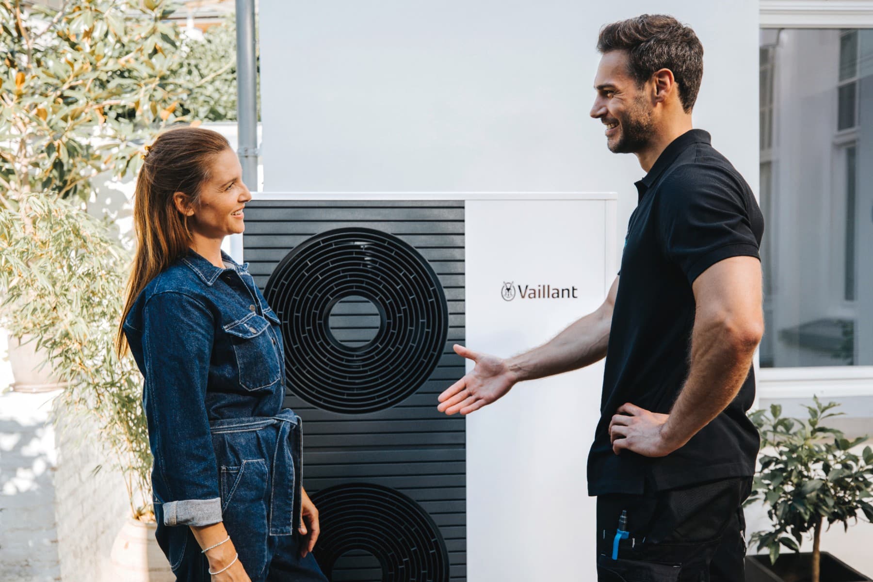 Una mujer y un técnico de Vaillant se dan la mano delante de una bomba de calor