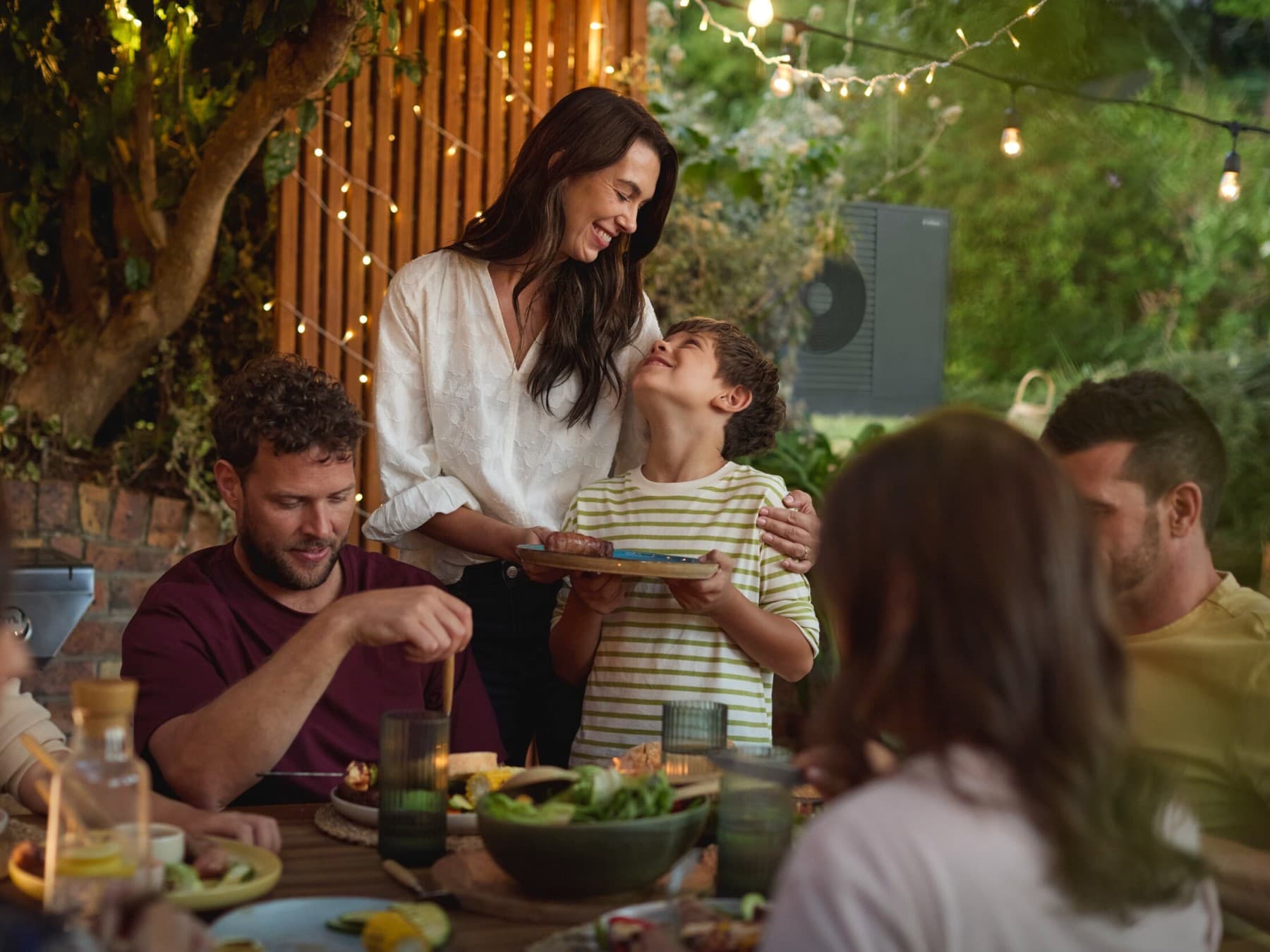 Familia disfrutando de una barbacoa en el jardín con amigos.