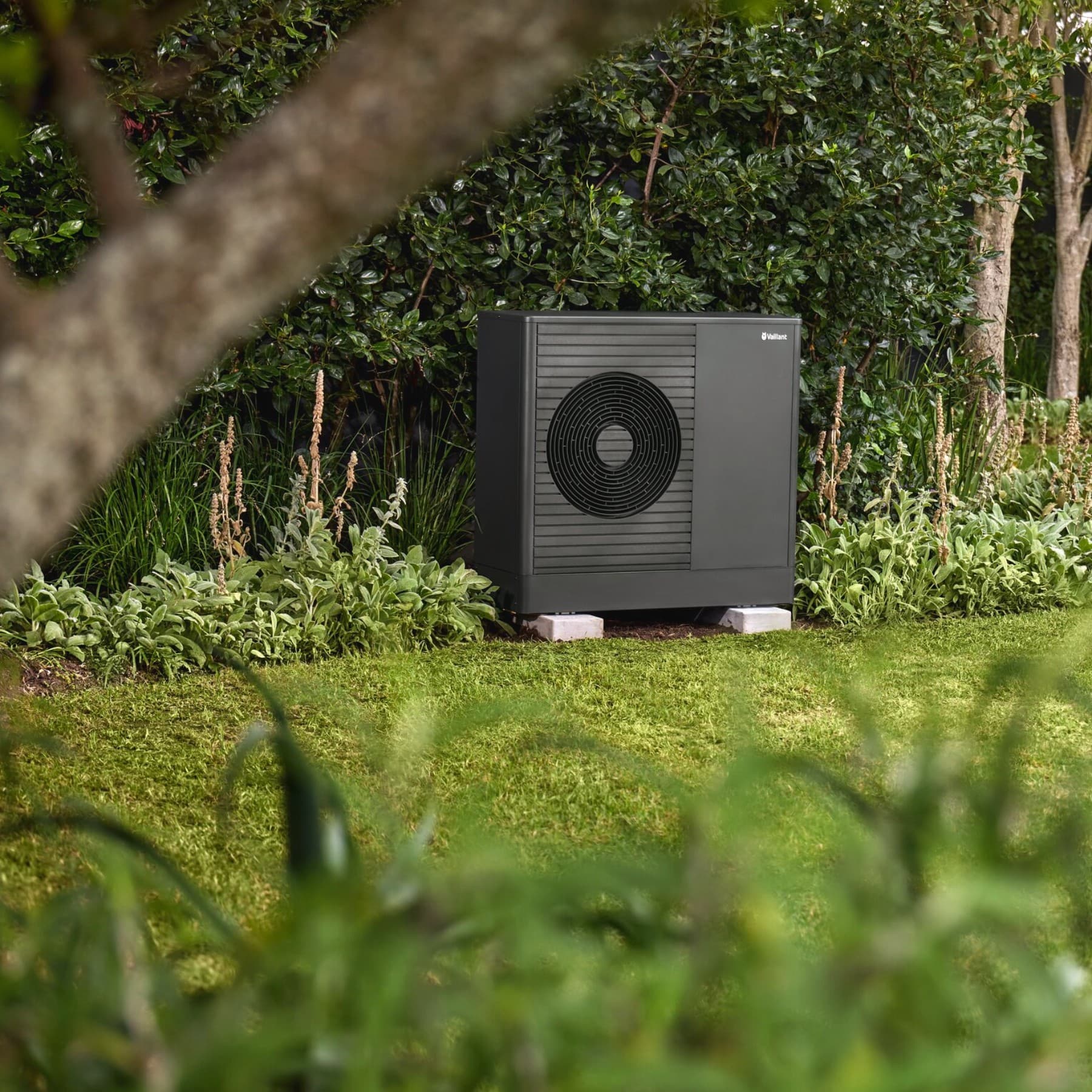 Bomba de calor Vaillant en el jardín, delante de una casa.