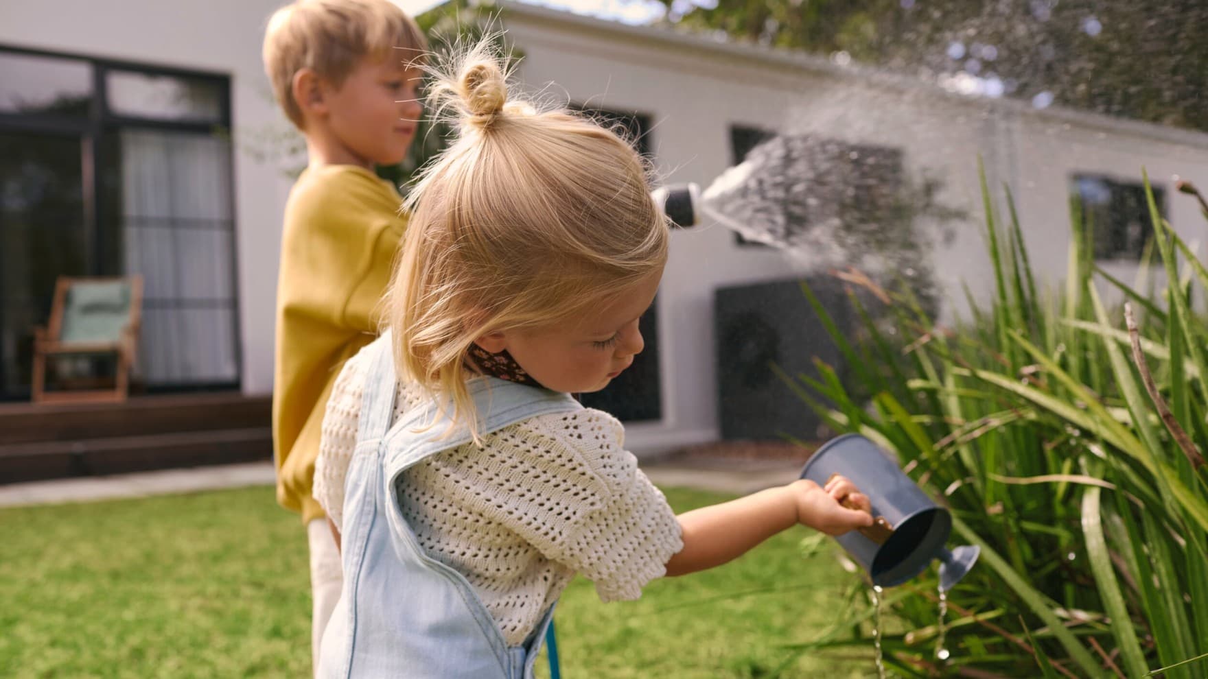 Niños regando plantas con una bomba de calor de fondo