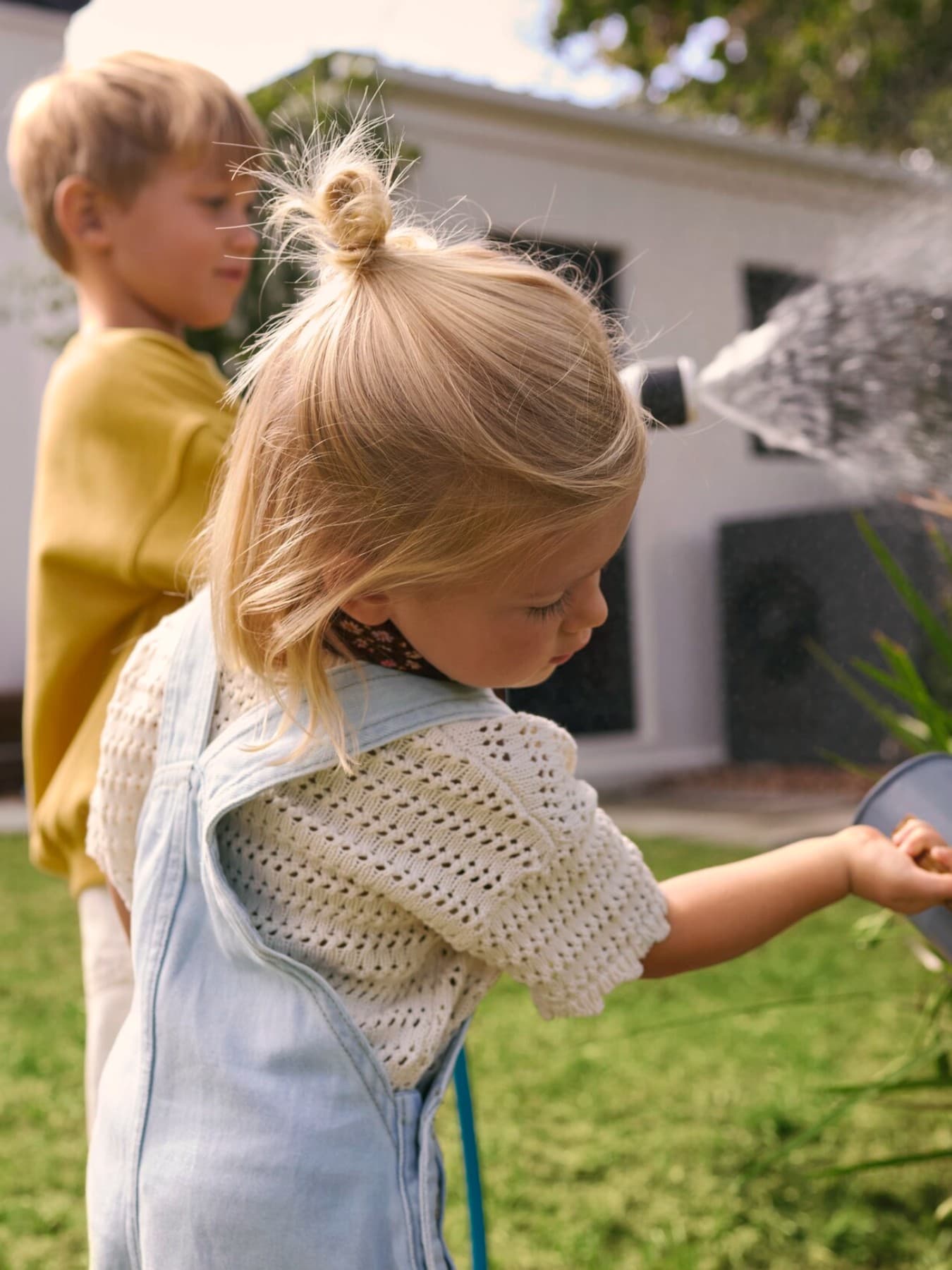 Niños regando plantas con una bomba de calor de fondo