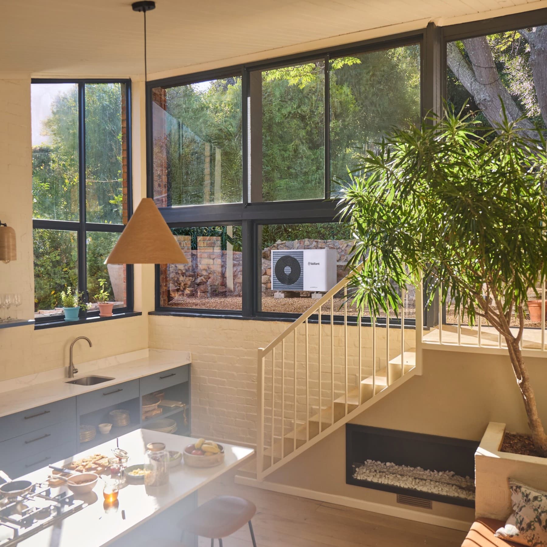 Una moderna cocina; al fondo en el jardín se ve una bomba de calor.