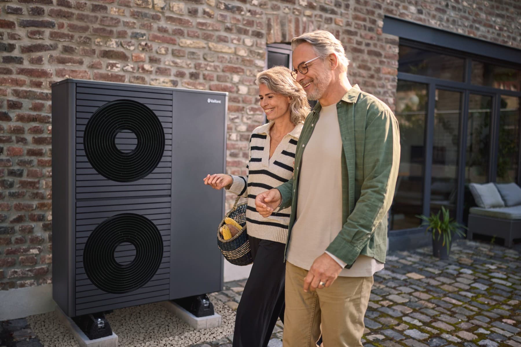 Pareja de mediana edad delante de una bomba de calor Vaillant.