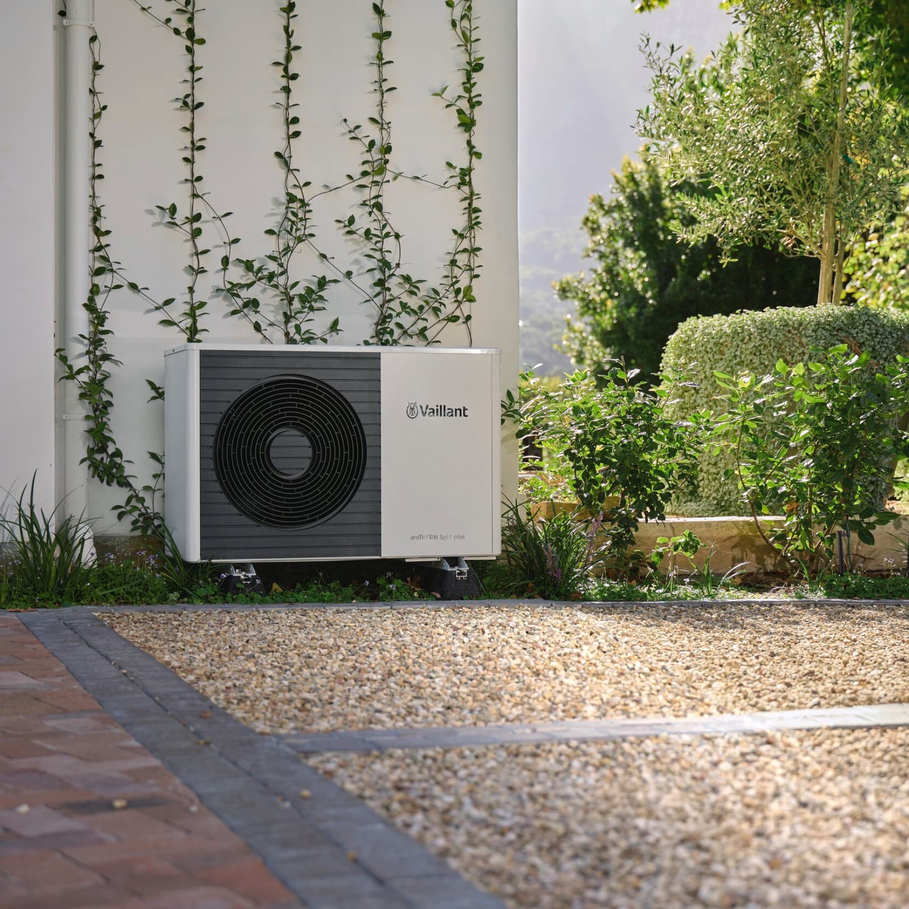 Bomba de calor Vaillant situada frente a una pared en un jardín.