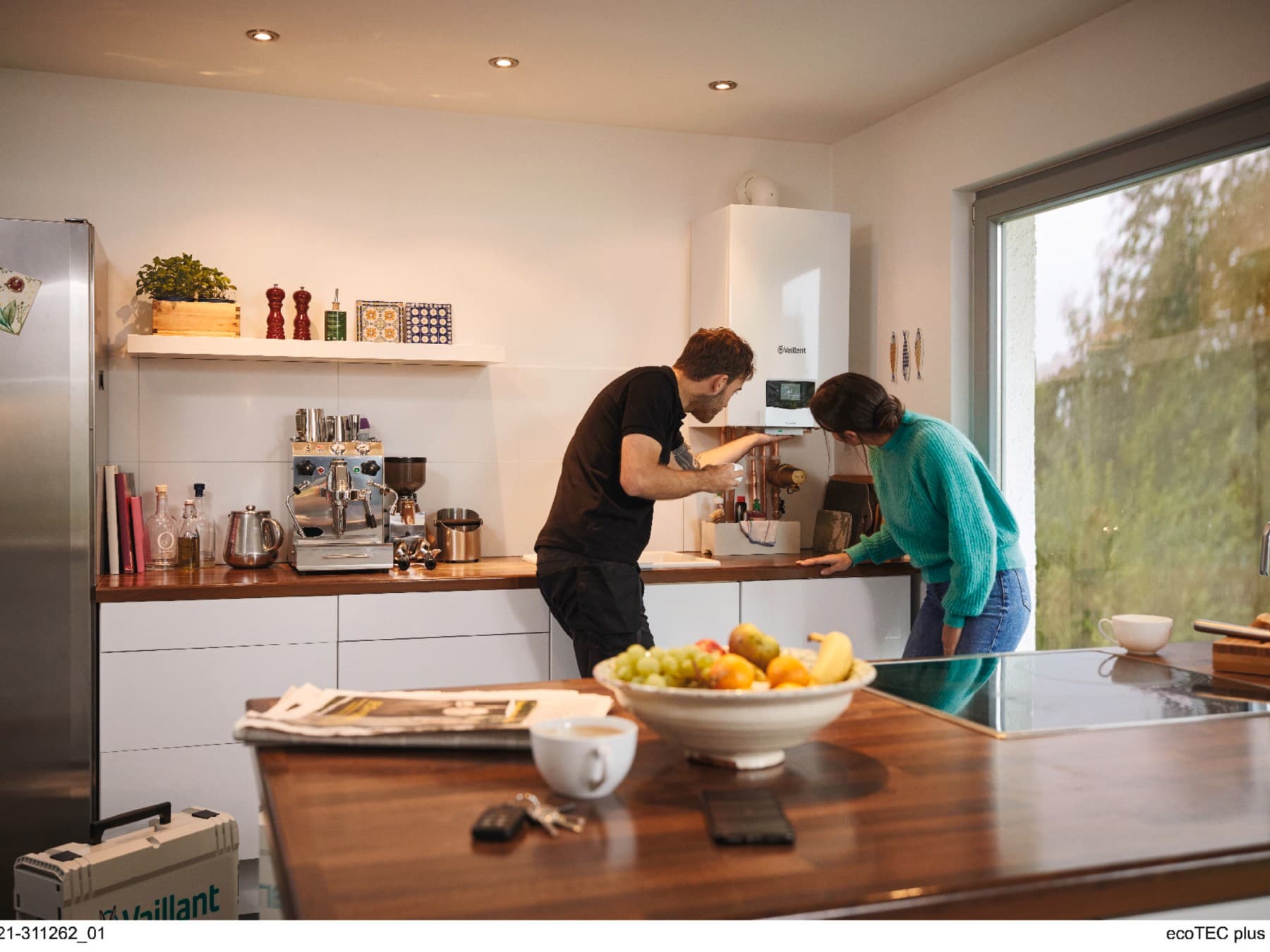 Mujer con un técnico familiarizándose con la nueva caldera instalada en su cocina.