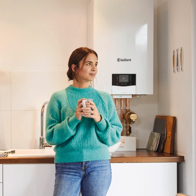 Mujer en su cocina tomando un cafe y detrás, su caldera ecoTEC exclusive